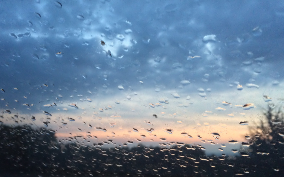 Regentropfen auf einem Dachfenster zum Sonnenuntergang.